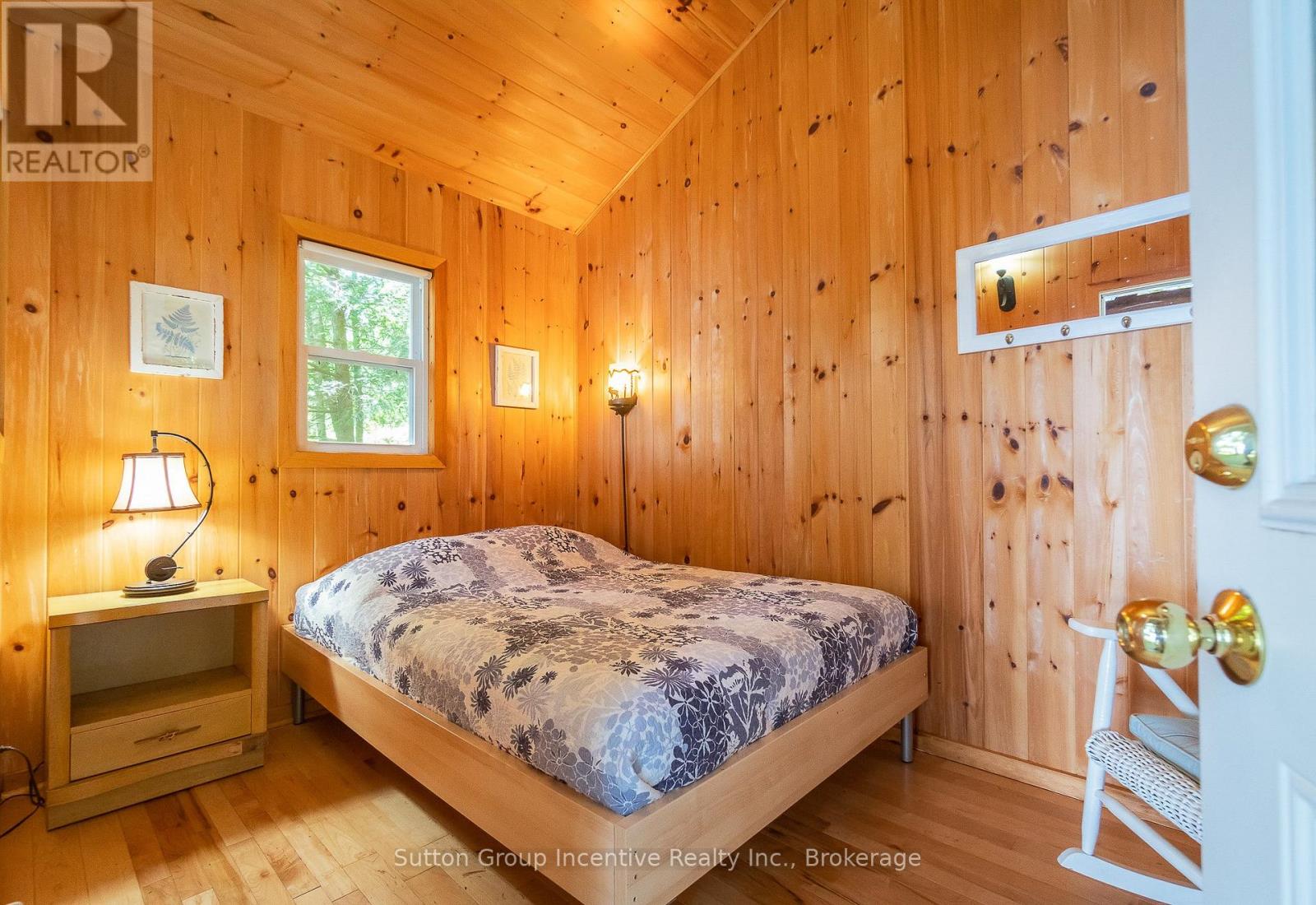 A bedroom with wooden walls and a bed with a blue and white patterned comforter.