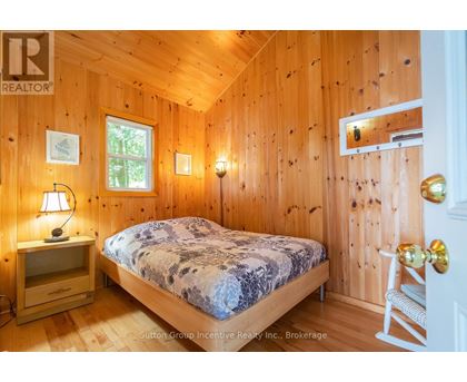 A bedroom with wooden walls and a bed with a blue and white patterned comforter.