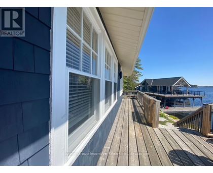 A wooden deck leads to a house with a blue exterior.