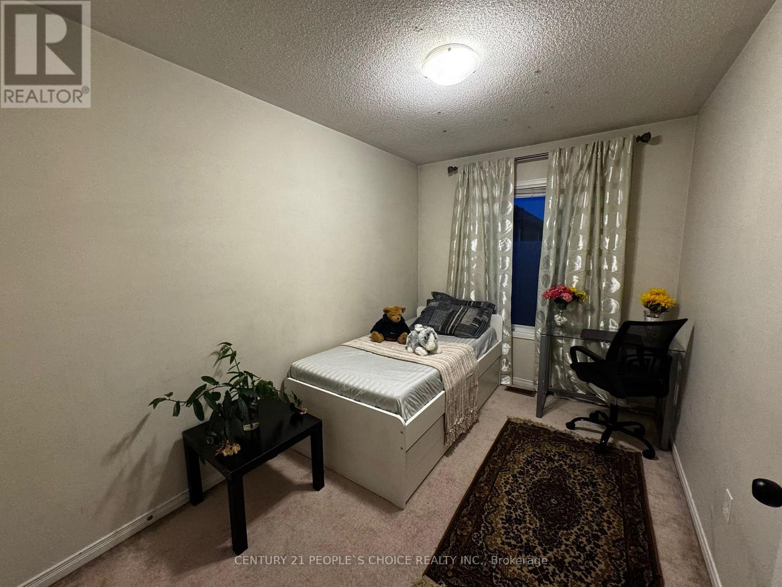 A bedroom with a bed, chair, and plant.