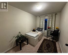 A bedroom with a bed, chair, and plant.