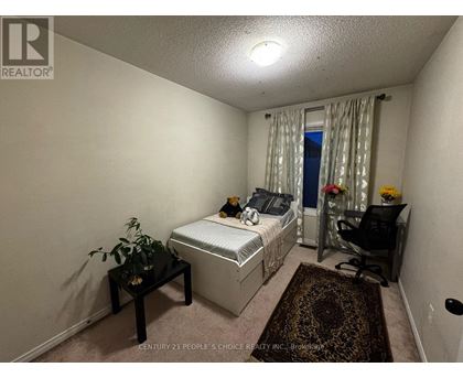 A bedroom with a bed, chair, and plant.