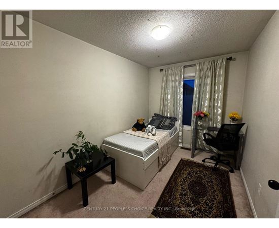 A bedroom with a bed, chair, and plant.