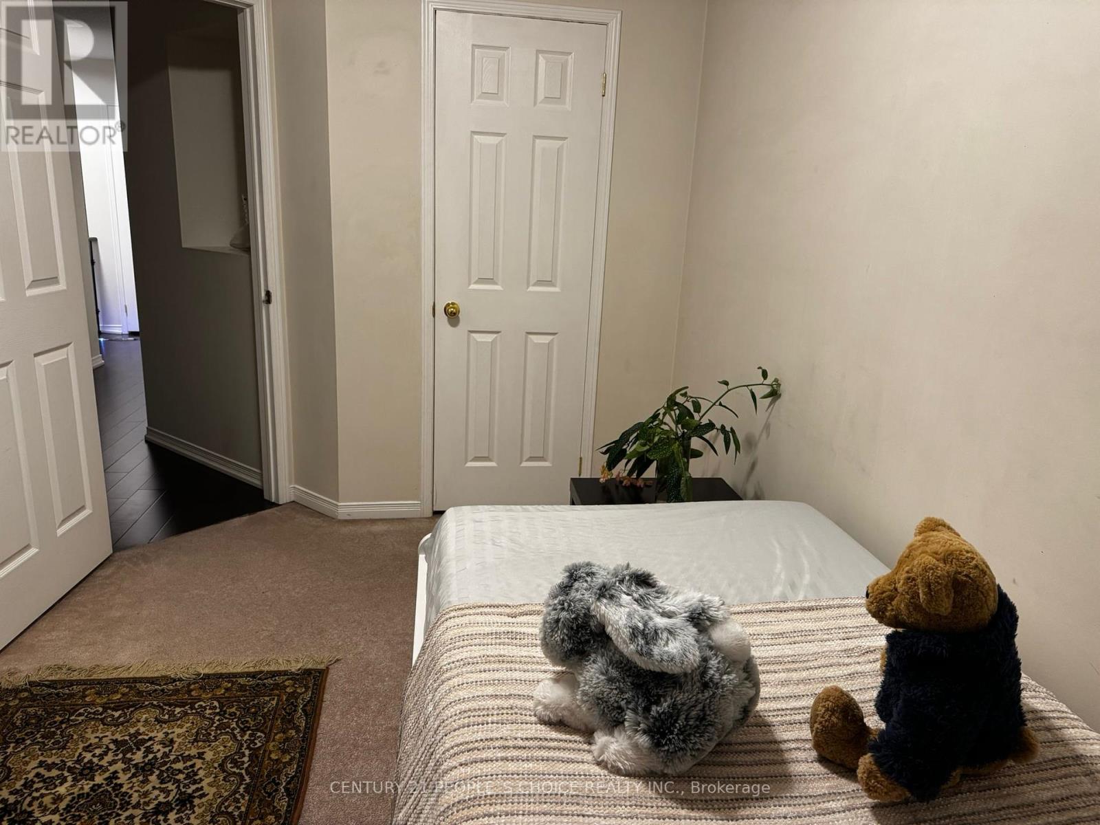 Teddy bears sitting on a bed in a room with a door and a plant.