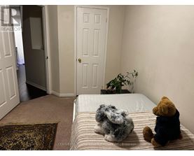Teddy bears sitting on a bed in a room with a door and a plant.