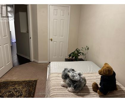 Teddy bears sitting on a bed in a room with a door and a plant.