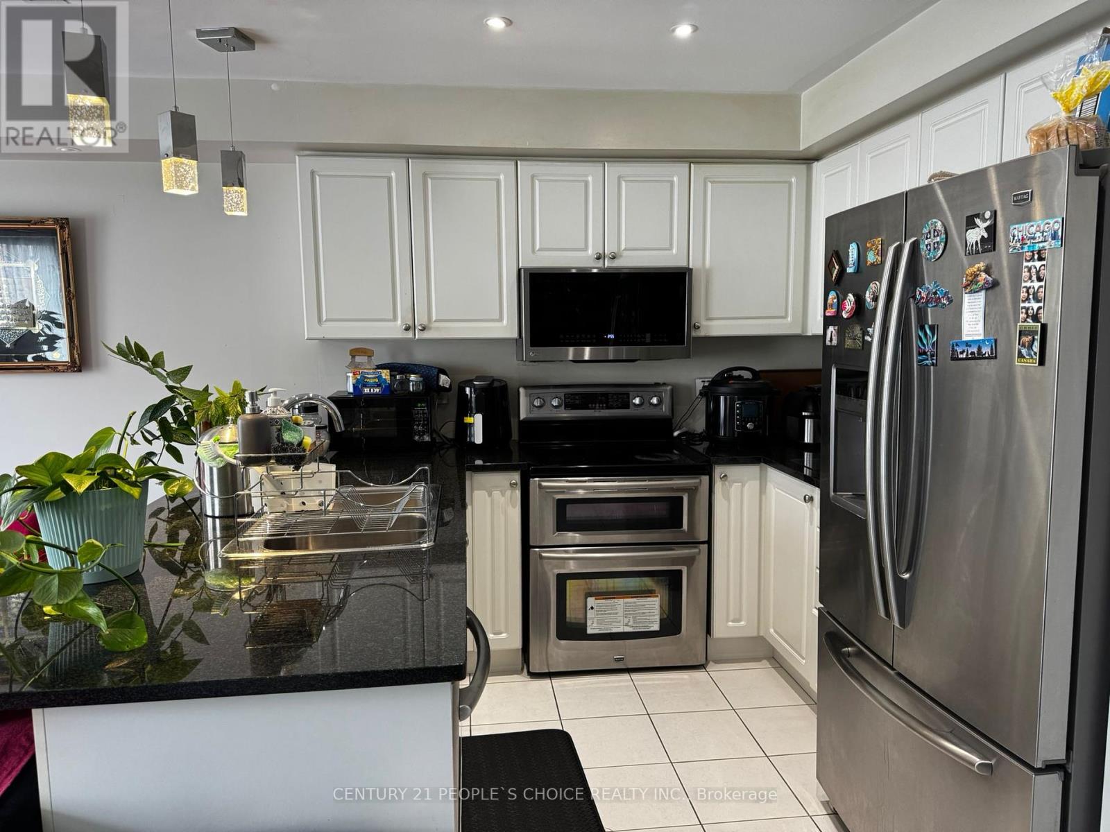 A kitchen with a black counter top and stainless steel appliances.