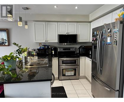 A kitchen with a black counter top and stainless steel appliances.