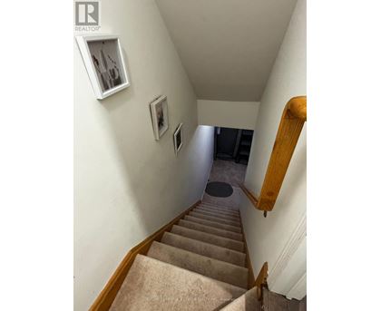 A staircase with beige carpet and wooden handrails.