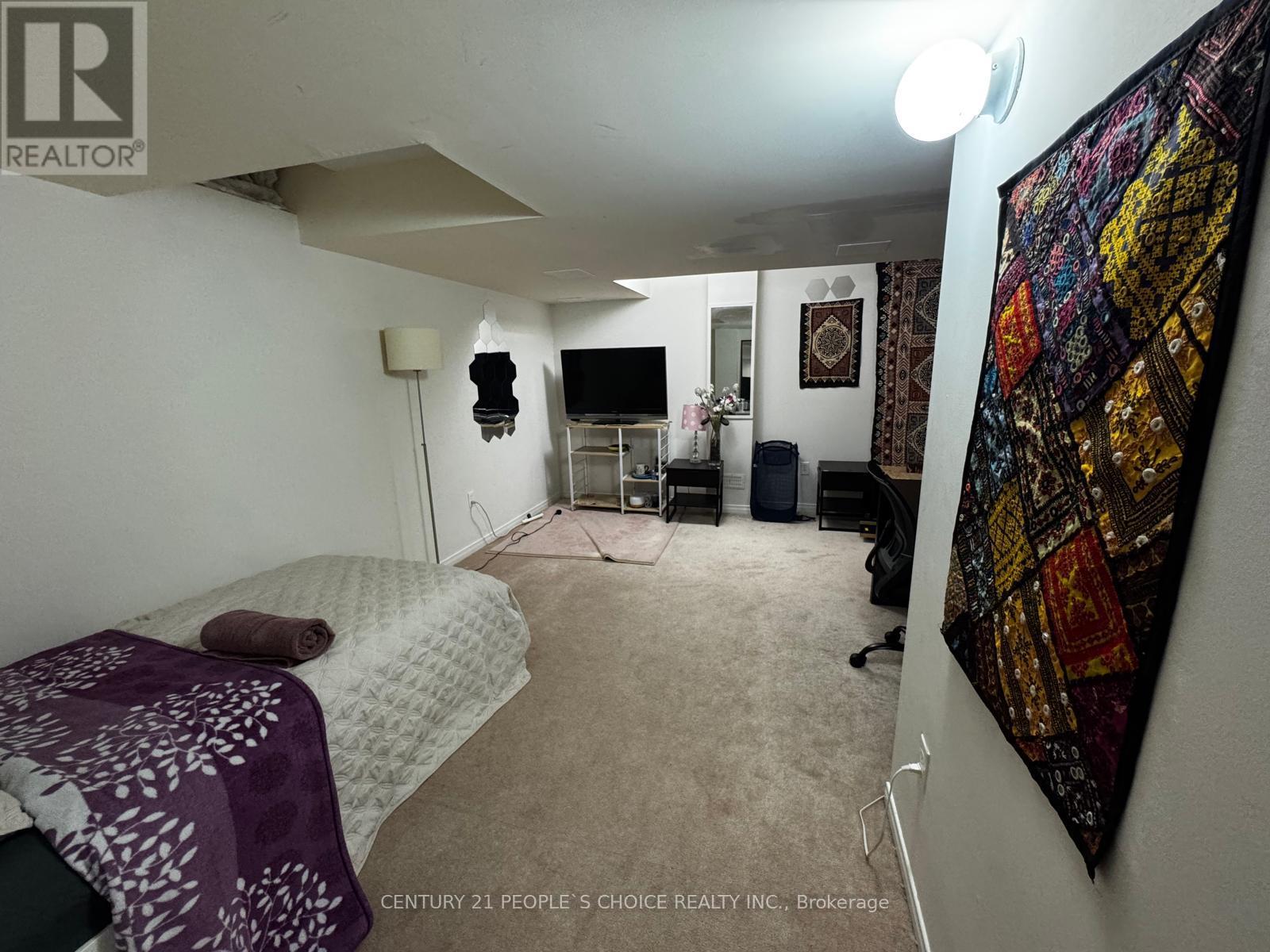 A bedroom with a bed, a chair, and a wall hanging.