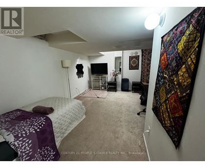 A bedroom with a bed, a chair, and a wall hanging.