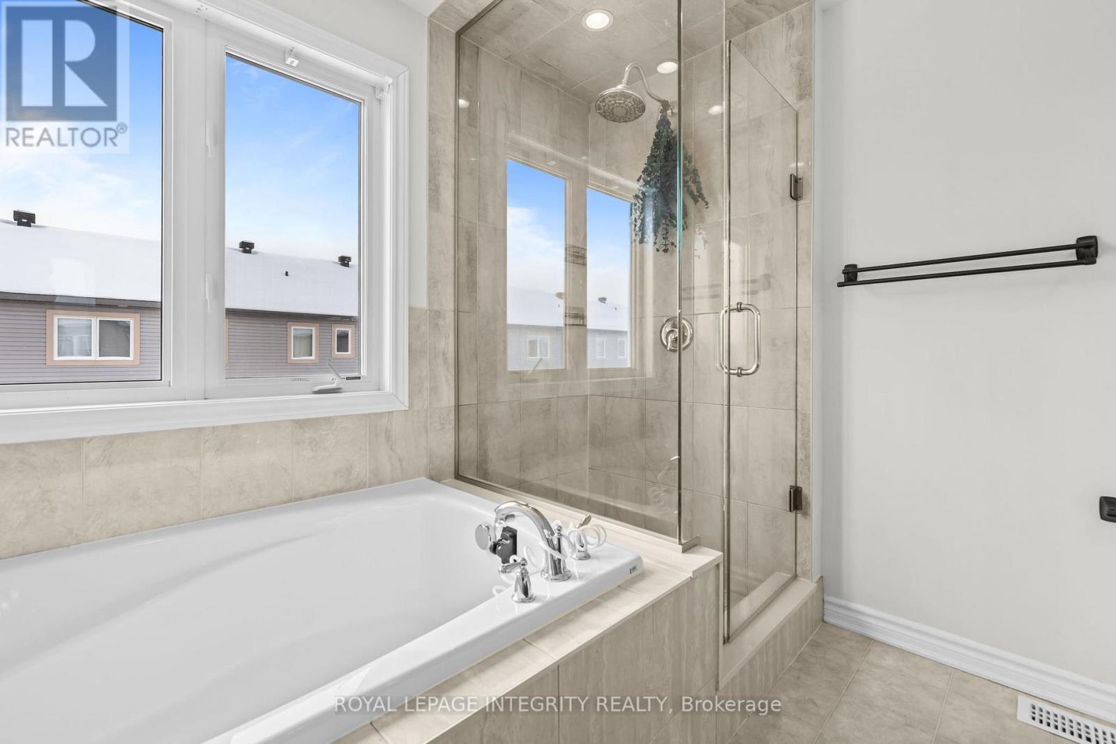 A bathroom with a tub and a window showing a view of other buildings.