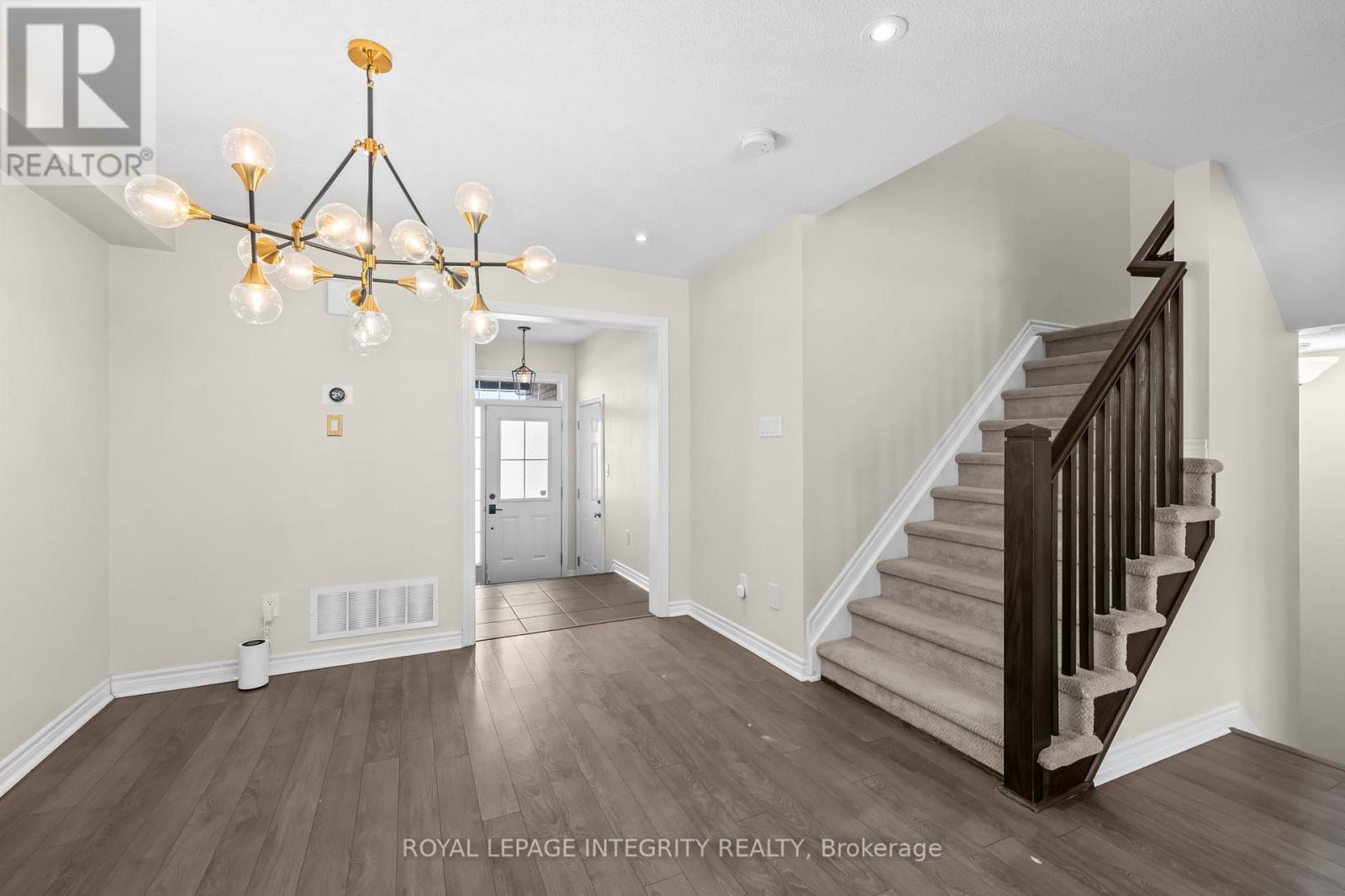 A spacious room with a staircase and a chandelier.