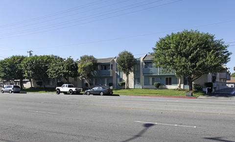A street view with cars and a building in the background.