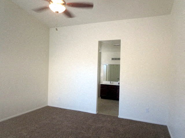 an empty living room with a ceiling fan