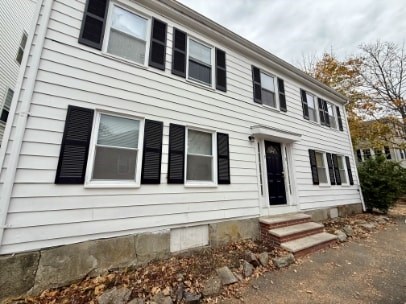 A white house with black shutters and a black door.