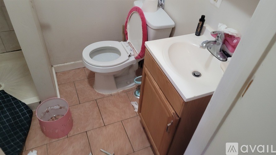 A bathroom with a toilet, sink, and a trash can.