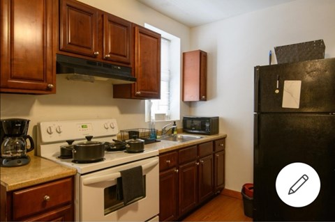 A kitchen with a black refrigerator and white stove.