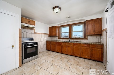 A kitchen with a stove top oven and wooden cabinets.
