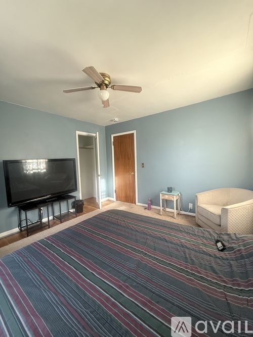 A bed with a white headboard and a blue pillow is in a room with floral curtains.