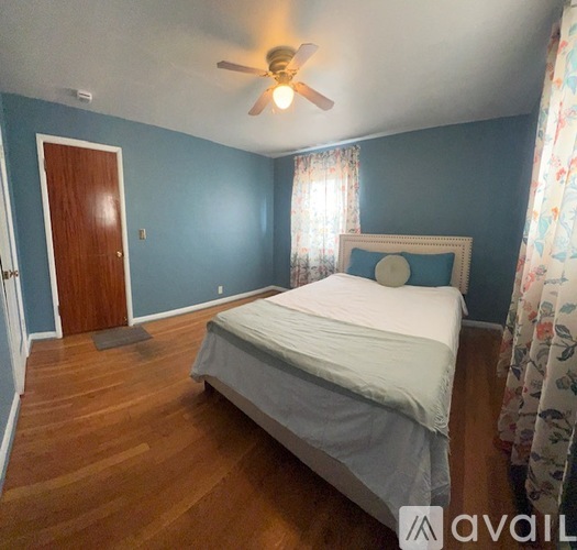 A bedroom with a bed, a ceiling fan, and a door.