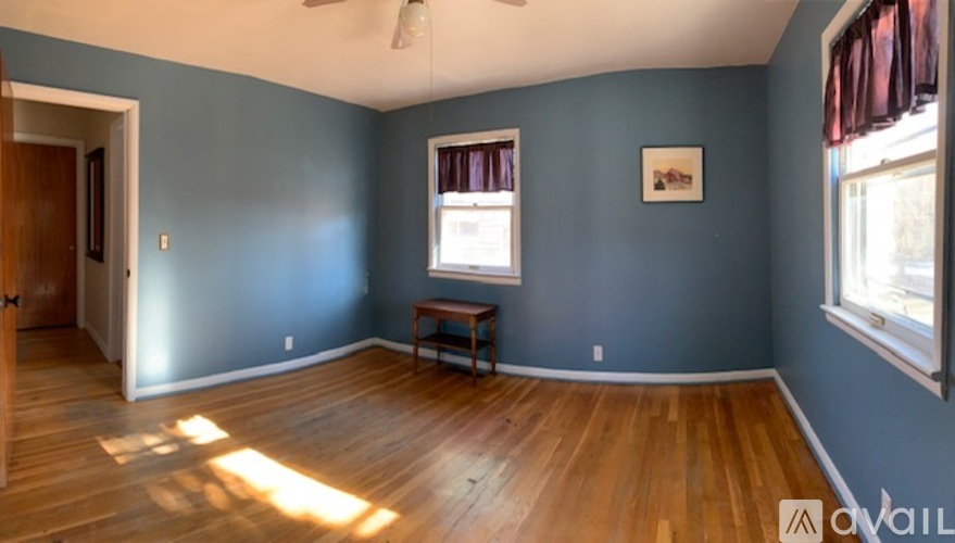 A room with a wooden floor and a window with red curtains.