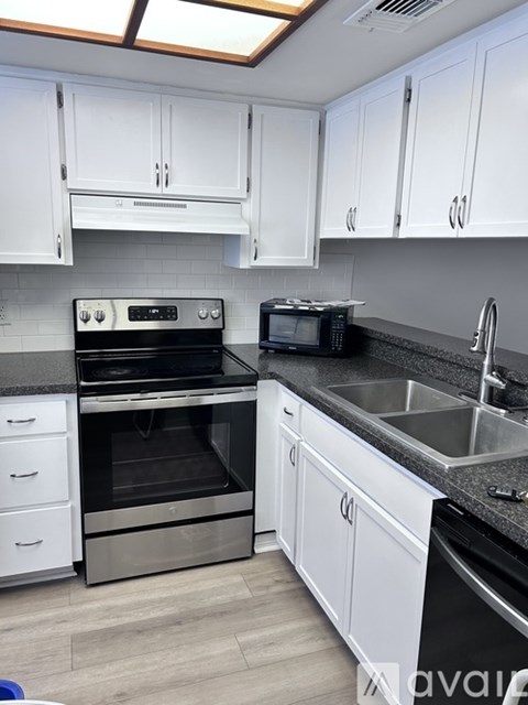 A kitchen with white cabinets and a black countertop.