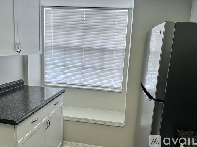 A kitchen with white cabinets and a black countertop.