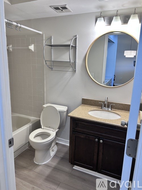 A bathroom with a toilet, sink, and mirror.