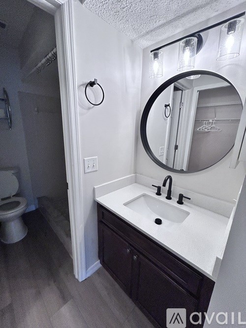 A bathroom with a toilet, sink, and mirror.