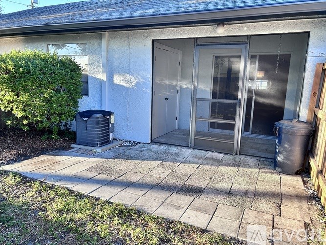 A small house with a grey door and windows, a grey trash can, and a grey trash bin.