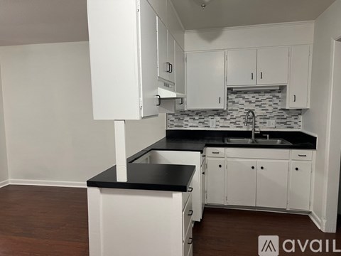 A kitchen with white cabinets and a black countertop.