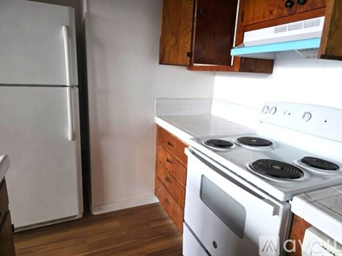A white stove with four burners is in a kitchen with wooden cabinets.