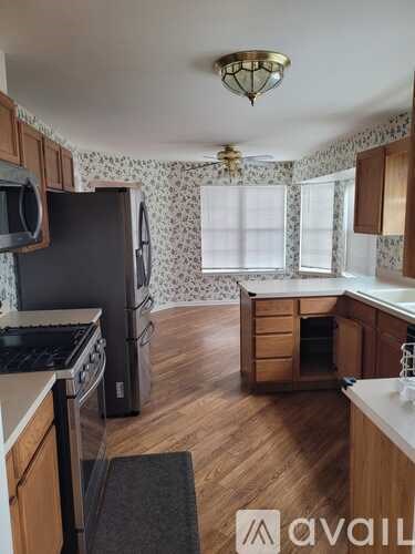 A kitchen with wooden cabinets and a black refrigerator.