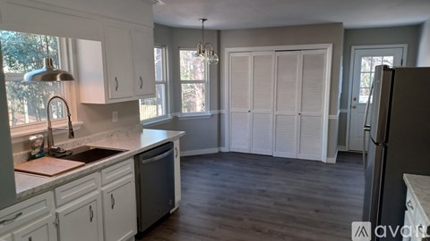 A kitchen with white cabinets and a wooden floor.