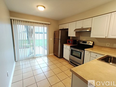 A kitchen with white cabinets and a tiled floor.