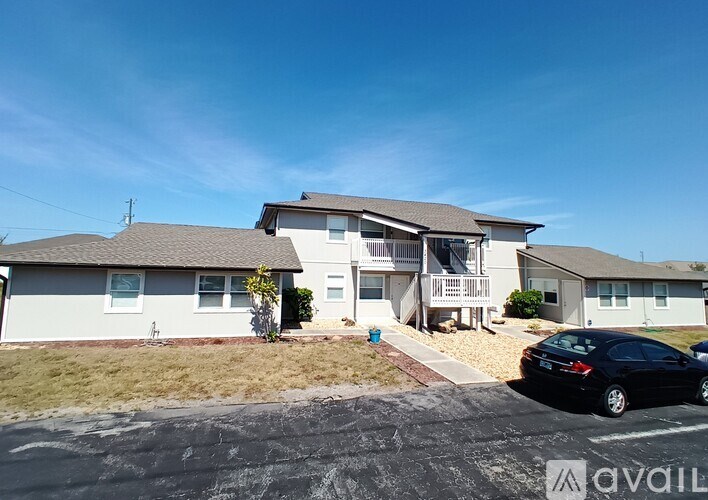 A black car is parked in front of a two-story house.