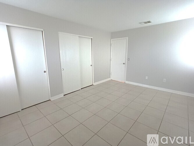 A room with white doors and tiled flooring.