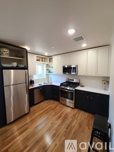 A modern kitchen with wooden floors and stainless steel appliances.