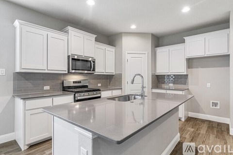 A kitchen with white cabinets and a grey countertop.