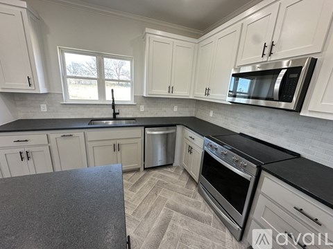 A kitchen with white cabinets and black countertops.