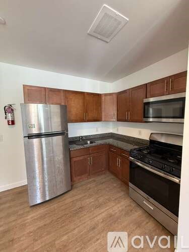 A kitchen with wooden cabinets and a stainless steel refrigerator.