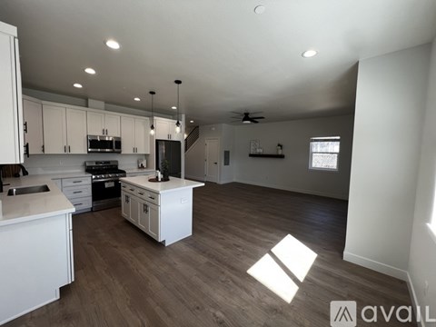 A spacious kitchen with white cabinets and a wooden floor.