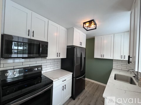 A kitchen with white cabinets and black appliances.