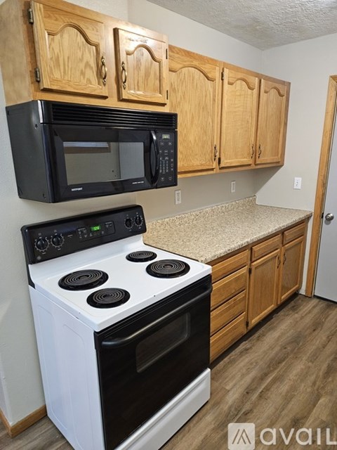 A kitchen with wooden cabinets and a black microwave above the stove.