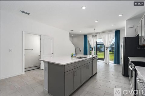 A modern kitchen with a large island and a refrigerator.
