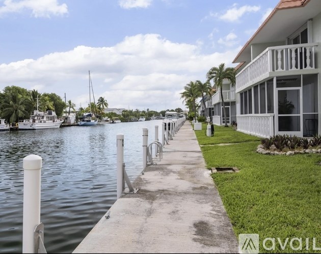 A row of white bollards line a concrete walkway next to a body of water.