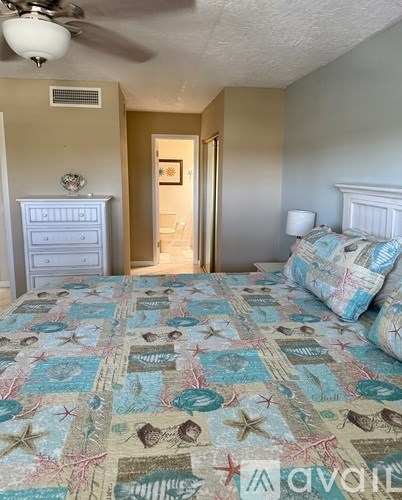 A bedroom with a bed, dresser, and ceiling fan.