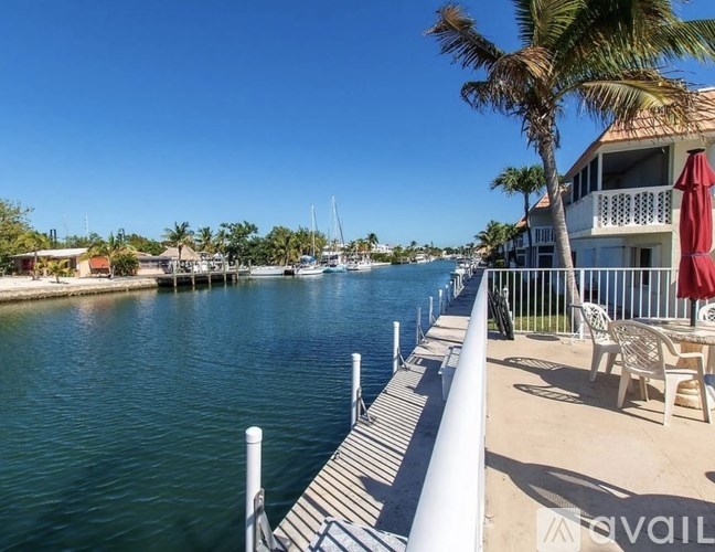 A dock with a white railing and a red umbrella.