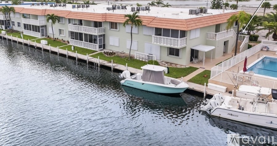 A boat is docked at a pier in front of a building with a pool.